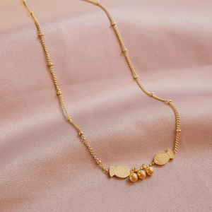 Gold-plated fish pendant necklace with delicate beaded chain on pink silk fabric