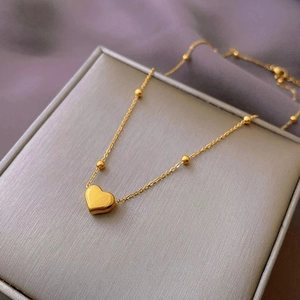 Macro shot of gold heart pendant necklace with bead chain on elegant jewelry display box