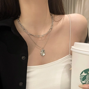 Close-up of a double-layered silver necklace with paperclip chain and lava pendant