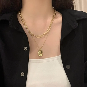 Double-layered gold necklace featuring a paperclip chain and irregular lava pendant