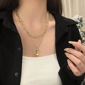 Close-up of double-layered gold paperclip chain necklace with irregular lava pendant