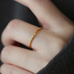 Close-up of minimalist gold ring with fine zircon stone on woman's hand