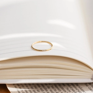 Close-up of a slim gold ring with three micro-zirconia stones on a white book page