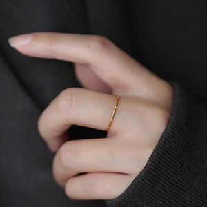 Macro shot of minimalist gold thin ring with a single small zircon on model finger