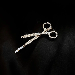 Sparkling silver scissors hair clip with white rhinestones on black satin background