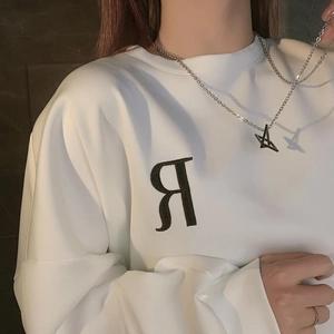 Detail der silbernen Titanstahlkette mit Stern und Buchstabe A Anhänger auf weißem Hoodie