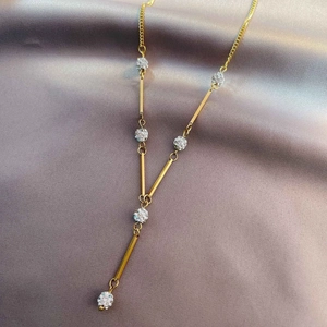 Elegant gold-plated Y-shaped lariat necklace with pavé crystal balls on silk background