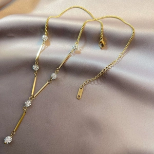 Elegant gold Y-shaped stainless steel necklace with crystal pavé ball on silk fabric