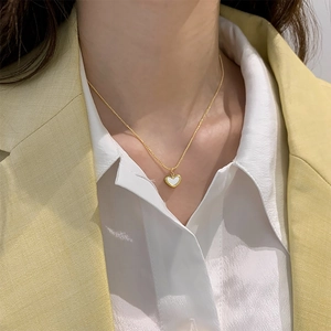 Elegant gold heart pendant necklace for women worn with a stylish white shirt and blazer