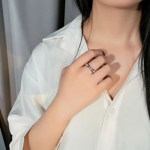 Close-up of a minimalist black and white textured ring on a finger with silk shirt background