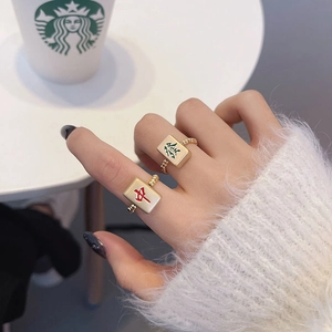 Detailopname van gouden Mahjong-ringen met Red Zhong en Green Fa tekens op vingers