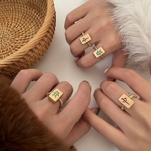Detailopname van vergulde Mahjong-ringen met rode en groene tekens op kralenkettingbanden