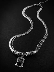 Detalle de collar plateado de doble capa con cadena de serpiente y piedra negra en cuero
