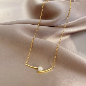 Minimalistische gouden titanium ketting met parel op een luxe zijden achtergrond