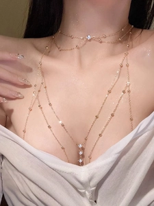 Detail of a layered gold body chain with shimmering rhinestones on a female model