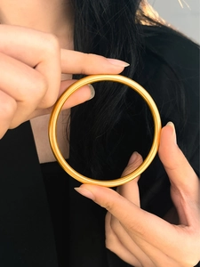 Primo piano di un braccialetto rigido dorato minimalista sulle mani della modella