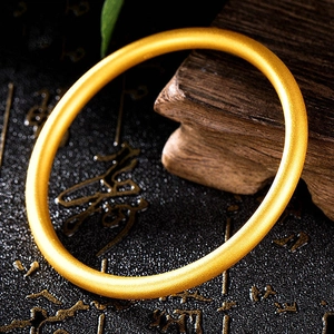 Classico bracciale rigido rotondo placcato oro in un elegante ambiente minimalista