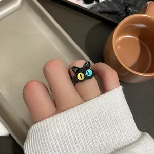 Detail of cute black cat ring with heterochromia yellow and blue eyes on a finger