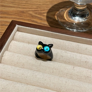 Nahaufnahme des matt-schwarzen Katzenrings mit blauem und gelbem Auge in einer Samtbox