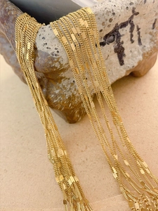 Détail macro de diverses chaînes à maillons croisés et plats gaufrés en acier doré