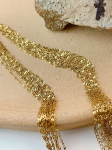 Gros plan de chaînes à maillons plats dorés à plusieurs rangs avec reflets brillants