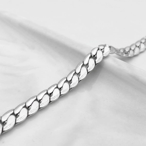 Dettaglio macro di catena cubana argento con maglie lucide e goffratura decorativa