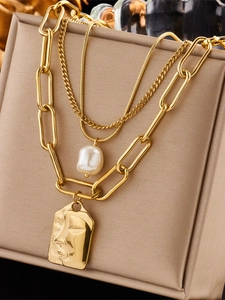 Close-up of gold layered necklace with baroque pearl and abstract face pendant