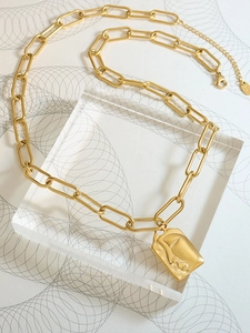Detailed macro view of the gold chunky link chain with an abstract face relief pendant