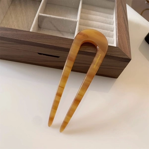 U-shaped hair fork in tortoiseshell acetate with elegant gold engraving on light background