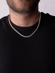 Detail of a silver rope chain necklace worn by a man over a black knit sweater