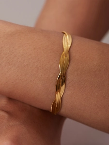 Macro shot of layered gold plated herringbone snake chain bracelet on person arm