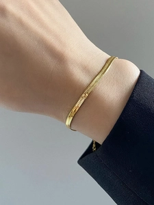 Bracelet chaîne serpent plat plaqué or avec pendentif cœur minimaliste sur le poignet