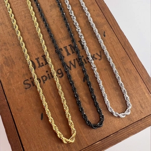 Detailed view of gold, silver, and black twist rope chains on a vintage wooden box