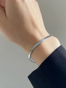 Bracelet chaîne serpent argentée avec pendentif cœur sur le poignet d'un mannequin femme