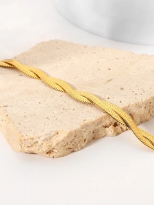 Close-up of double-layered gold snake bone chain bracelet on textured stone base