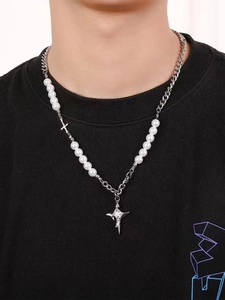 Dettaglio della collana di perle e catena d'argento con ciondolo a croce su modello
