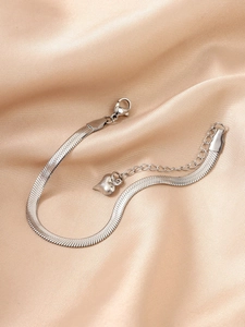 Bracelet chaîne serpent en acier argenté avec pendentif cœur sur fond de satin