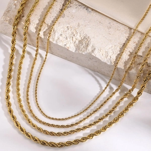 Polished gold plated stainless steel rope chains in various sizes on marble and silk