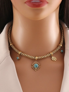 Détail du collier choker doré avec pendentif fleur, arbre de vie et pierres turquoise bleues