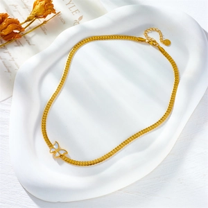 Vue détaillée d'un collier chaîne serpent dorée avec un pendentif papillon en nacre blanche
