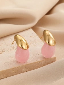 Détail de boucles d'oreilles pendantes rose marbré avec supports métalliques dorés