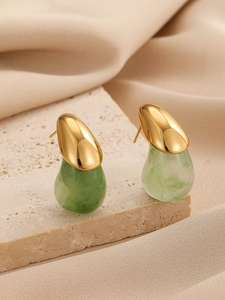 Vue macro détaillée des boucles d'oreilles en marbre vert sur fond de soie beige et pierre
