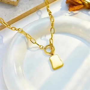 Detail view of a gold square pendant necklace with OT clasp on an oval link chain