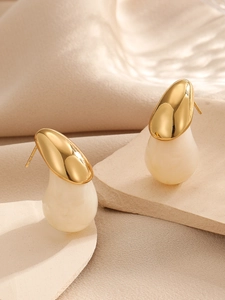 Gros plan du poinçon S925 sur boucles d'oreilles goutte en métal doré et pierre crème