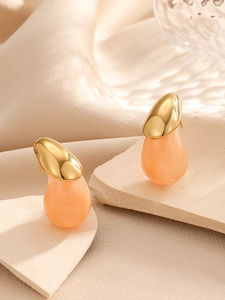 Détail de boucles d'oreilles dorées en forme de goutte avec breloques en résine pêche
