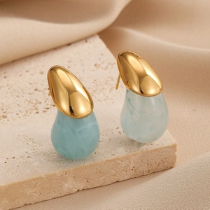 Boucles d'oreilles dorées avec gouttes de résine marbrée bleu clair sur support