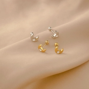 Detail of moon-shaped titanium steel stud earrings with cubic zirconia on silk cloth
