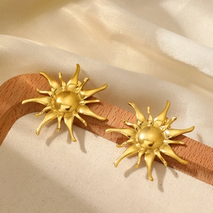 Minimalist gold sunburst stud earrings displayed on elegant white satin and wood stand