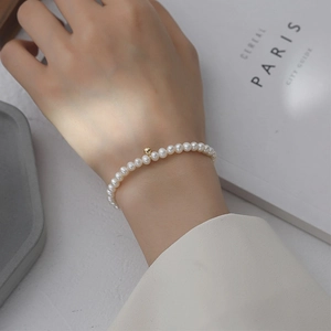 Elegant French vintage pearl bracelet with a gold bead accent worn on a wrist