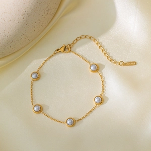 Elegante gouden roestvrijstalen armband met vijf parels op een zijden satijnen achtergrond